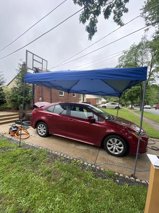 Red sedan being detailed under the mobile canopy